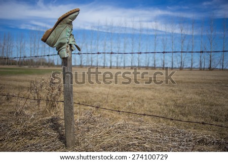 A green work boot hanging upside down on a fence post