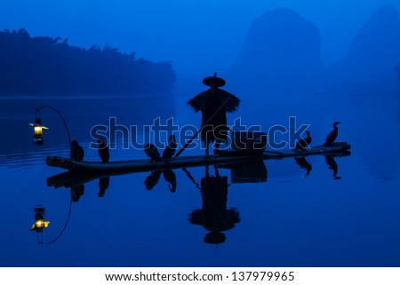 Shot on the Li River in Guilin, China during the blue hour of dawn and the photo depicts the ancient tradition of cormorant fishermen.  Title: Ancient Cormorant Fisherman of the Li River