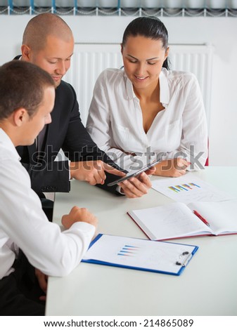 Image of people hand pointing at business document during discussion at meeting
