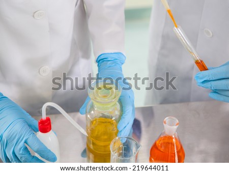 Attractive young female scientist and her male supervisor pipetting and microscoping in the life science research laboratory (biochemistry, genetics, forensics, microbiology..)