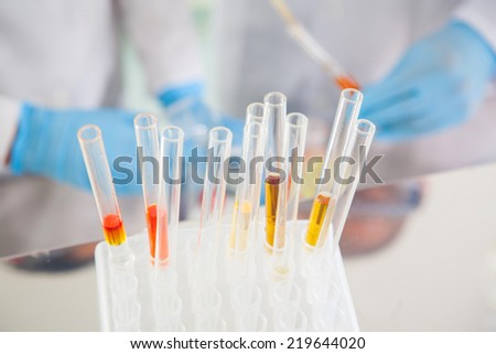 Female scientist and her male supervisor pipetting and microscoping in the life science research laboratory (biochemistry, genetics, forensics, microbiology..)