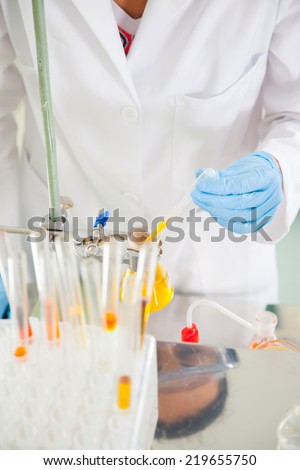Attractive young female scientist pipetting and microscoping in the life science research laboratory (biochemistry, genetics, forensics, microbiology..)