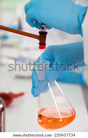beautiful researcher carrying out research experiments in a chemistry lab (color toned image)