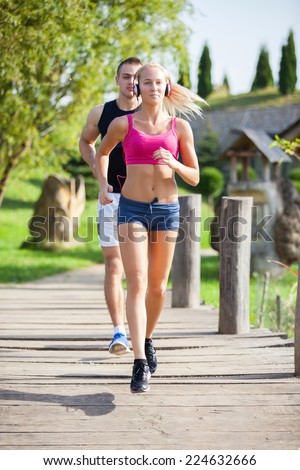 fitness, sport, friendship and lifestyle concept - smiling couple  running outdoors