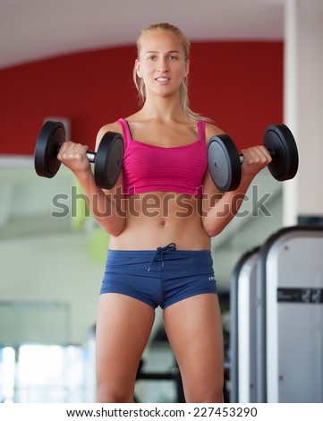Push-ups woman with dumbbells workout fitness club at weightlifting gym