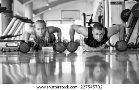 Gym man and woman push-up strength pushup with dumbbell in a fitness