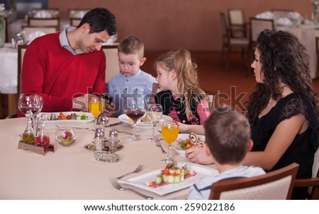 Waiter serving a family in a restaurant and bringing a full plate