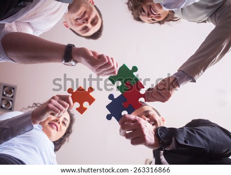 Group of business people assembling jigsaw puzzle and represent team support and help concept in office