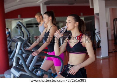 young women drinking water after sports. Fitness gym.