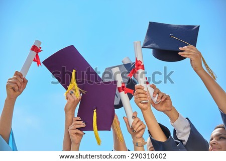 graduates stutents  throwing graduation hats in the air.