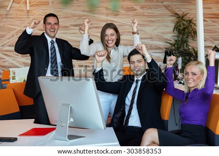 Business team celebrating a triumph in office with arms up
