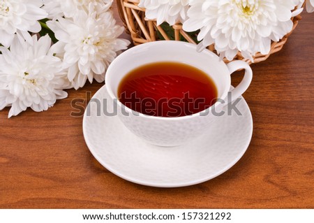 still-life with a glass full of tea and white chrysanthemums