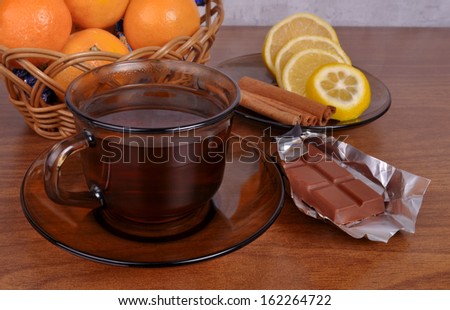 A cup with a fragrant tea with lemon slices and chocolate in a foil on a wooden table