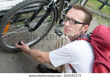 man pump up the bike wheel outdoor on the city street