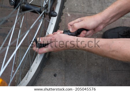 man pump up the bike wheel outdoor on the city street close up