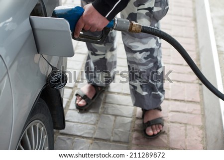 Pumping gas at gas pump. Closeup of casual man pumping gasoline fuel in car at gas station.
