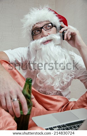 Santa Claus sitting in bed, drinking beer, calling e-shop with a mobile phone, makes request  for xmas gifts