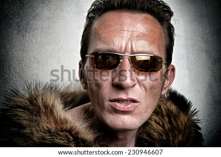 young angry guy in sunglasses and a fur coat looking at the camera. close up portrait