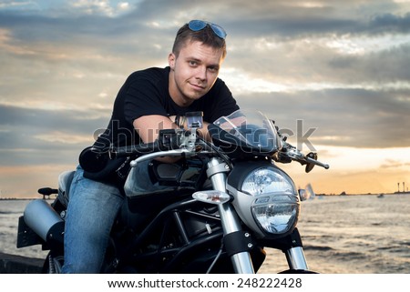 Friendly guy on a motorcycle smiling at the camera in the evening outdoor