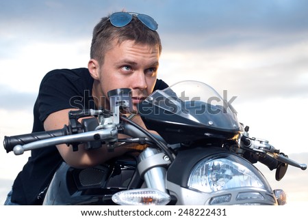 young man with a stubborn look leaned on the steering wheel of his bike