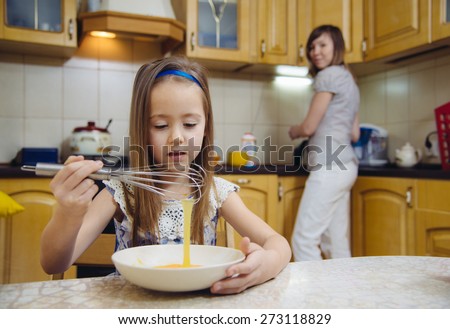 little  mothers helper. Small girl going to beat the dough for pancakes. Mom teach daughter to cook