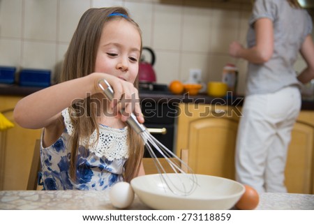 little  mothers helper. Small girl going to beat the dough for pancakes. Mom teach daughter to cook