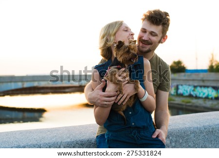 happy handsome young couple with small dog embracing and laughing