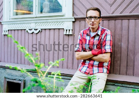 Man in casual clothes and rubber working gloves near his country house. copy space left