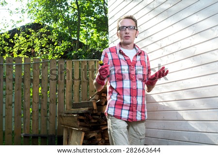 Man in casual clothes and rubber working gloves near his country house in perplexity