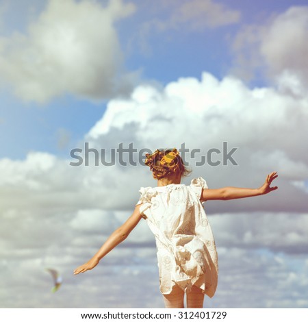 Happy small girl running at the background of high sky with clouds. Freedom concept.