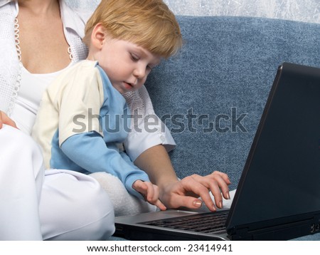 Young mum with the small beautiful boy together sit near laptop