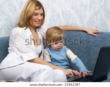 Young mum with the small beautiful boy together sit near laptop
