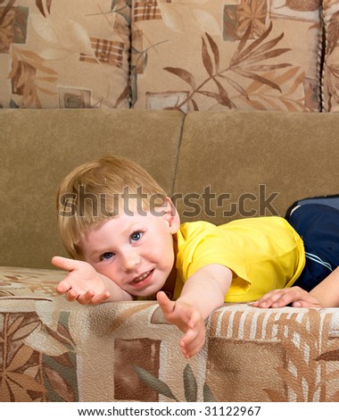 The little boy lays on a sofa of the house