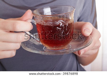 The attractive girl holds a glass with tea in hands