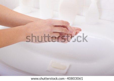 Washing of hands above a bowl in a bathroom