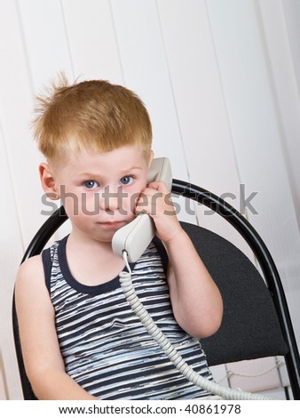 The little boy sits with a telephone tube in hands