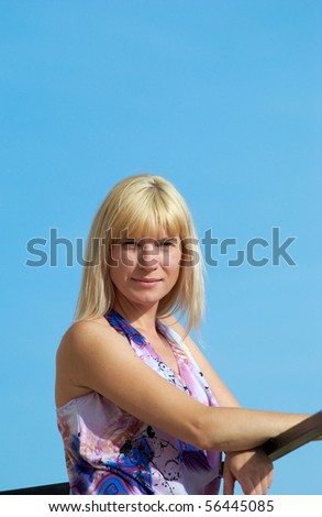 The young woman poses with the lifted hands on a background of the dark blue sky
