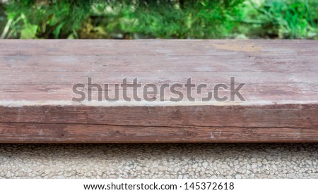 Wood surface on stone base over green grass background
