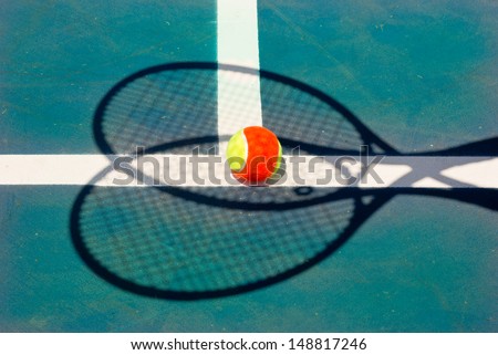 Tennis ball and two racquets shadow