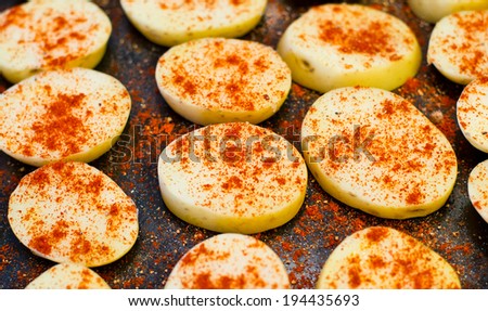 Potatoes slices covered by red pepper before cooking.
