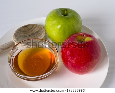 Honey and two apples on white plate.