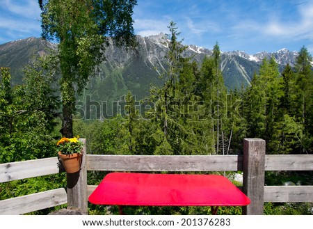 Red empty table at mountain cafe over the Alps landscape.