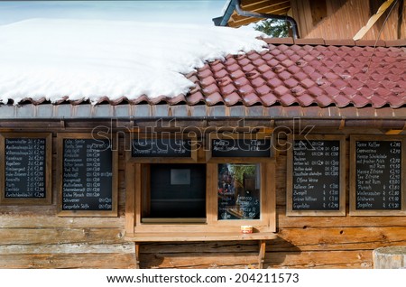 ELLMAU, AUSTRIA - JANUARY 29, 2014 : Wood chalet bar with typical Austrian drinking menu, written on windows at ski slope of Ellmau, Austria on January 29, 2014.