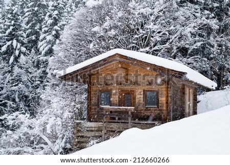 Scenery of small wood chalet over  snow covered trees on slope of Austrian ski resort.