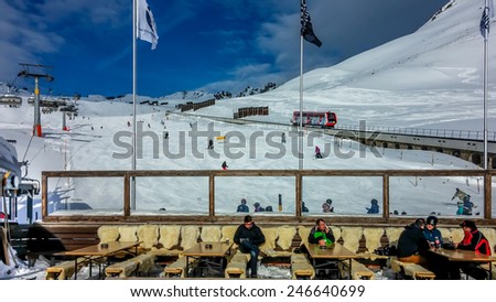 DAVOS, SWITZERLAND - JANUARY 15, 2015 : Unidentified skiers at mountain restaurant  over slope and train track of Davos, Switzerland.