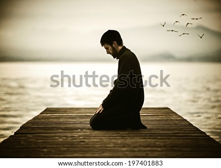Muslim man fasting Ramadan and praying on beautiful lake (old look photo with noise added)