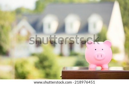 Real estate sale, home savings, loans market concept. Housing industry mortgage plan and residential tax saving strategy. Piggy bank isolated outside home on background. Focus on piggybank. Homeowner