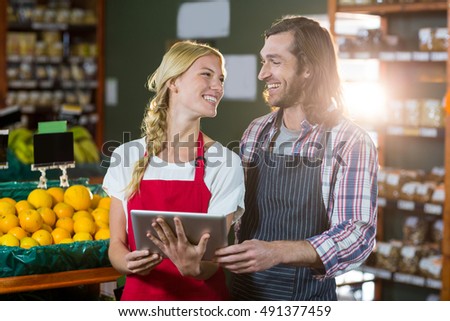Smiling staffs using digital tablet in organic section of super market