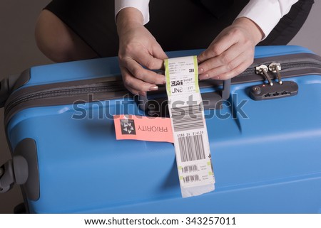 Airline check in luggage tag being attached to a suitcase. Priority tags