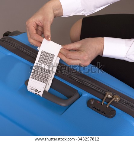 Airline check in luggage tag being attached to a suitcase